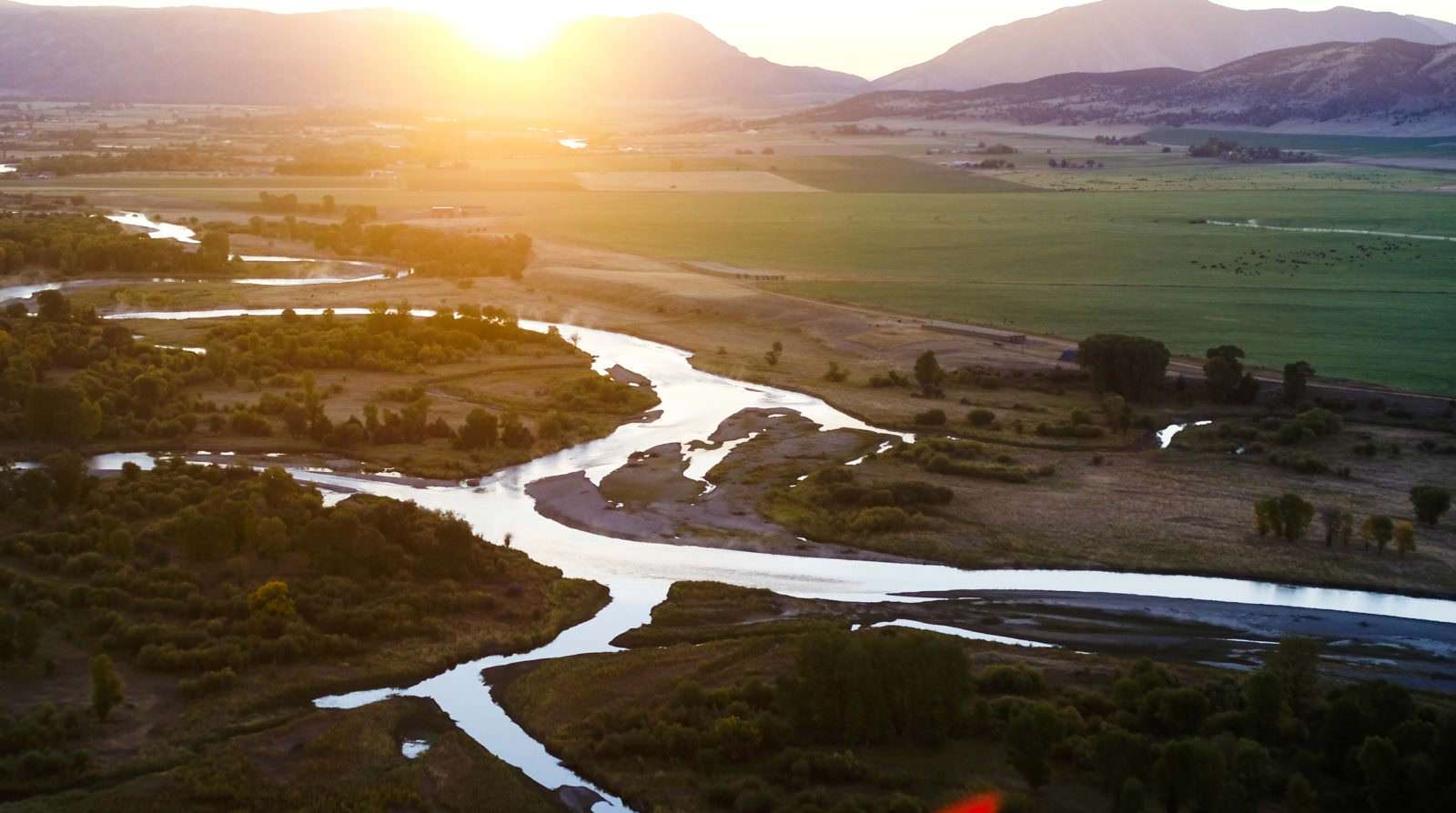 Winding river in front of mountains reflecting the sunset on a Montana ranch
