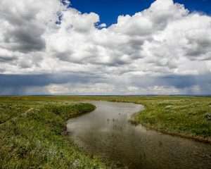 Curvy river reflecting clouds on Montana ranch for sale