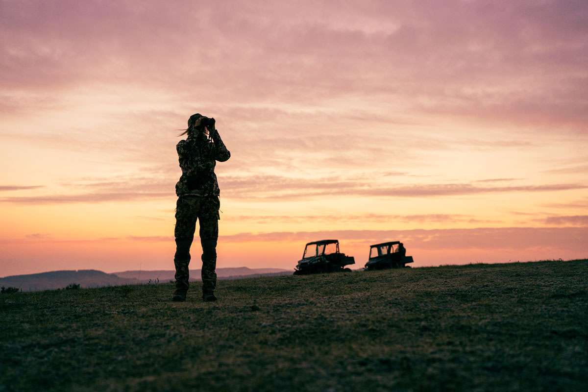 Western Ranch Brokers Morgan Zupan using binoculars at sunset on a Montana elk hunt